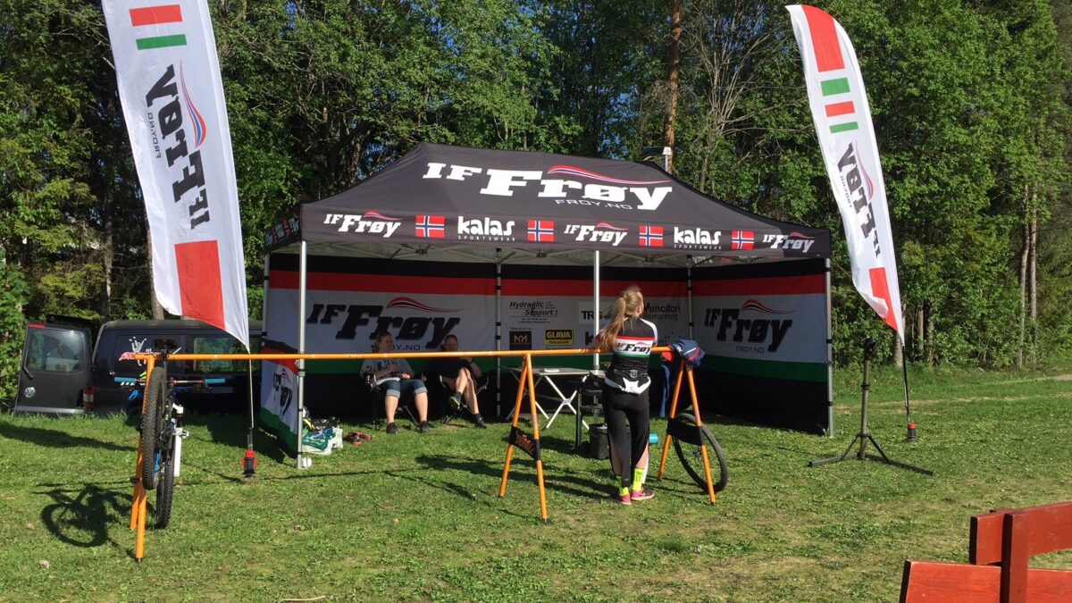 Namiot reklamowy z brandingiem IF Frøy, ustawiony na plenerowym wydarzeniu kolarskim. Namiot służy do prezentacji sprzętu i wsparcia dla kolarzy.