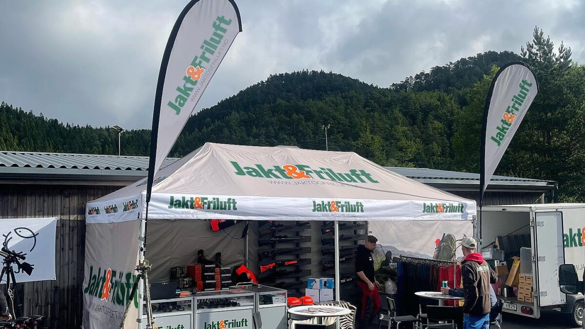 Namiot reklamowy od Hallgruppen z brandingiem Jakt & Friluft, ustawiony na wydarzeniu plenerowym z górami w tle. Namiot wykorzystywany jest na wystawy.