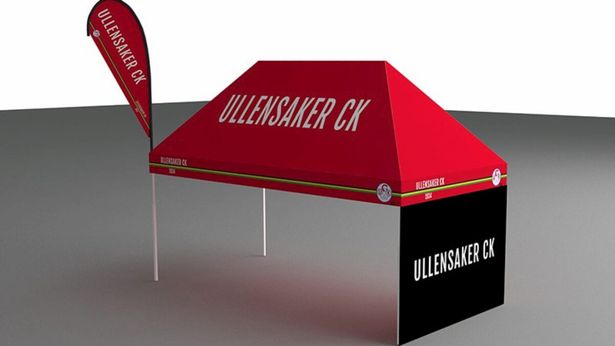 Czerwony namiot reklamowy z brandingiem Ullensaker CK ustawiony w strefie wystawowej. Namiot posiada pasującą flagę i jest wykorzystywany na wydarzenia związane z kolarstwem.