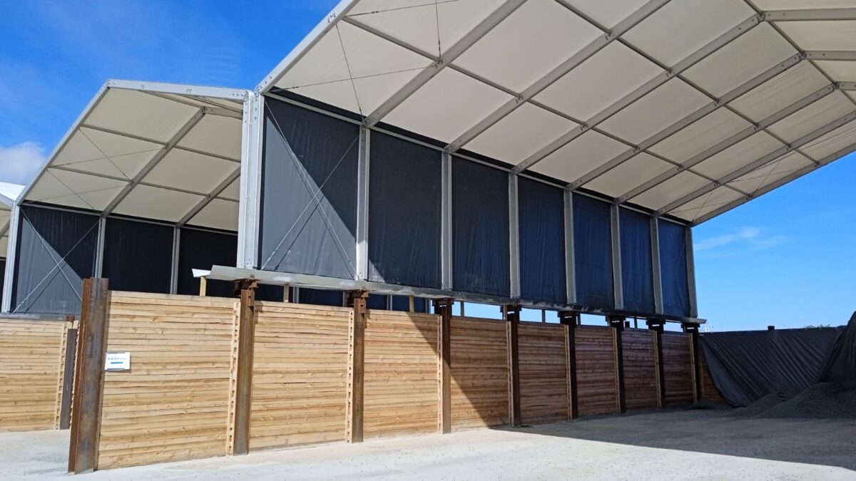 Hala przemysłowa od Hallgruppen z otwartą konstrukcją i drewnianymi barierkami, ustawiona na zewnętrznym placu roboczym.