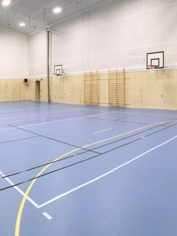 Hala sportowa z wieloma koszami do koszykówki oraz bramką do piłki ręcznej. Jasne wnętrze zostało zbudowane przez Hallgruppen z myślą o wszechstronnym zastosowaniu.